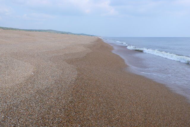 A pebbled beach with gentle waves lapping at the shore.