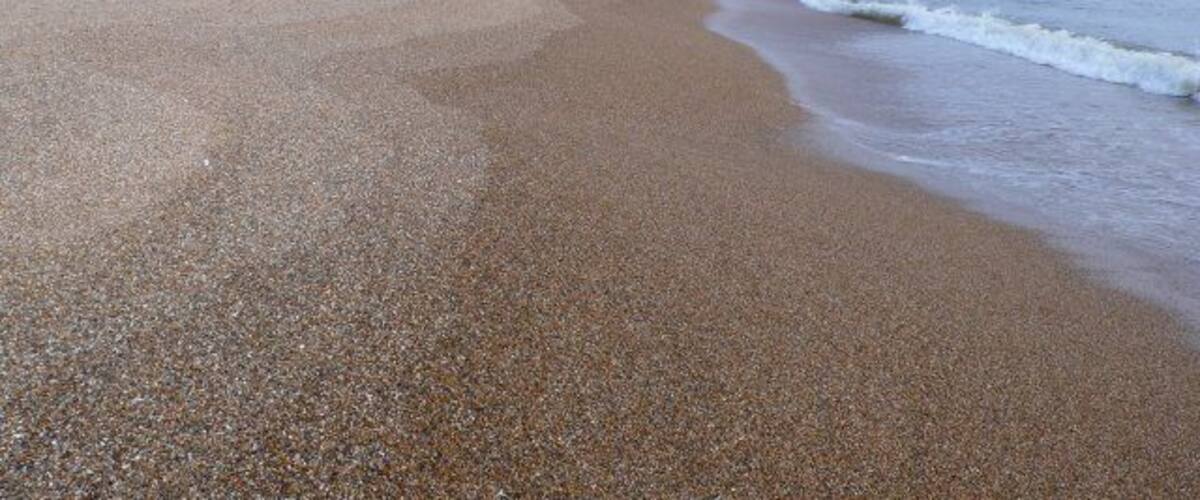 A pebbled beach with gentle waves lapping at the shore.