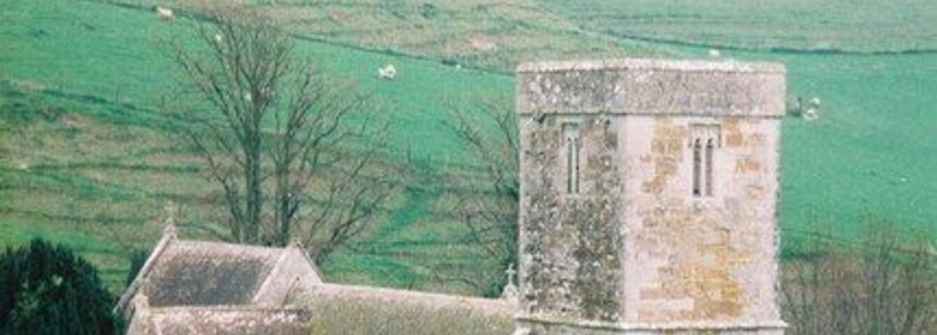 Una iglesia con un campanario y un molino de viento en un paisaje rural.
