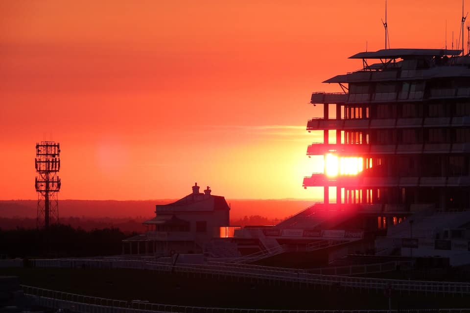 Un atardecer sobre un estadio con una alta torre de comunicaciones al frente.