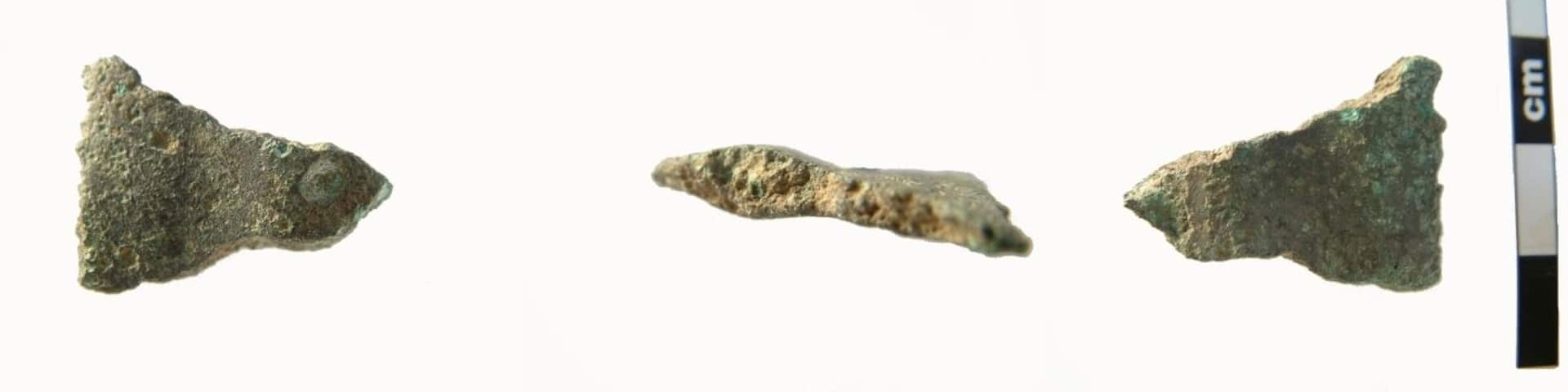 Possible fragment of Late Bronze Age sword of the Carps Tongue type. In section this fragment has a prominent mid-rib 5.4mm thick and c.10mm wide. One side of this is missing (probably recent damage). On the other side the blade extends c.11mm, thickening after it narrows either side of the mid-rib, then thinning towards the blade edge which is missing its bevelled edge, also due to recent damage. The metal is dark green in colour and has a rough feel. The fragment measures 26.7mm wide (probably originally c.38-40mm wide), is 20.1mm in length and max5.4mm thick. It weighs 7.01g. Carps Tongue swrods date from the 9th to 8th century BC.