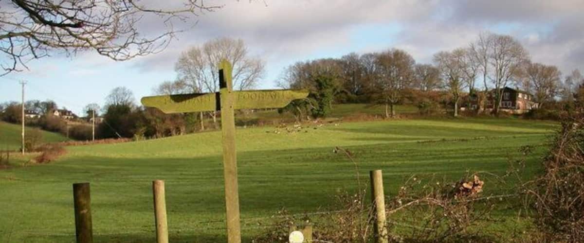 A wooden fence with a signpost in a rural setting.
