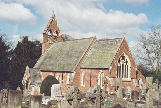 A church with a bell tower and a graveyard in front.