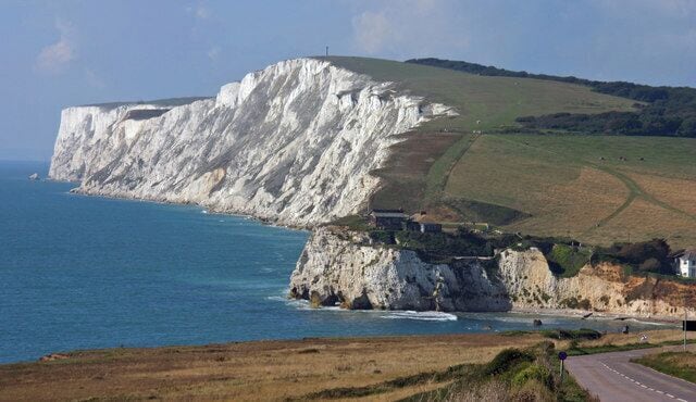 A coastal landscape with white cliffs, a road, and a clear sky.