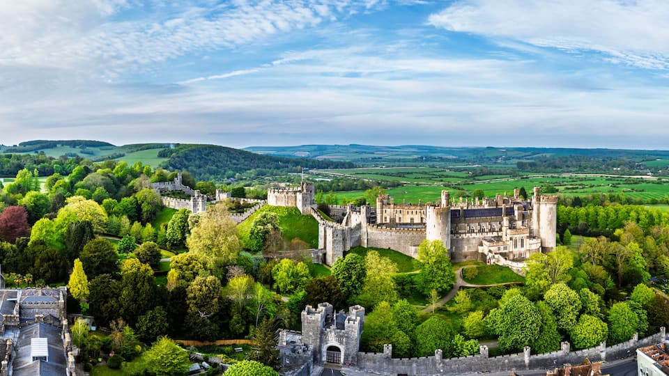 A historic castle surrounded by lush greenery and a small town.