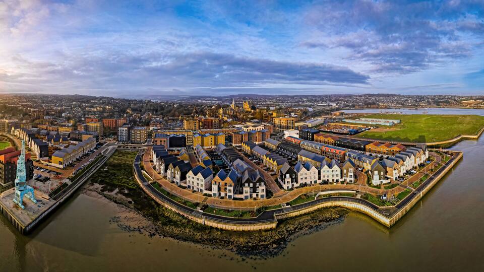 A waterfront cityscape with a prominent castle, a river, and surrounding urban development.