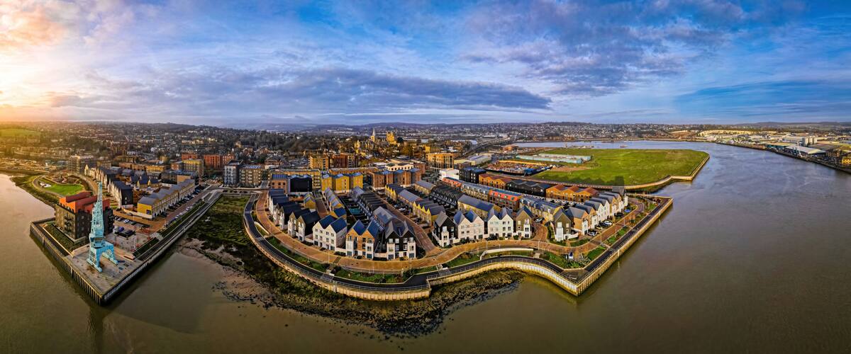 A waterfront cityscape with a prominent castle, a river, and surrounding urban development.