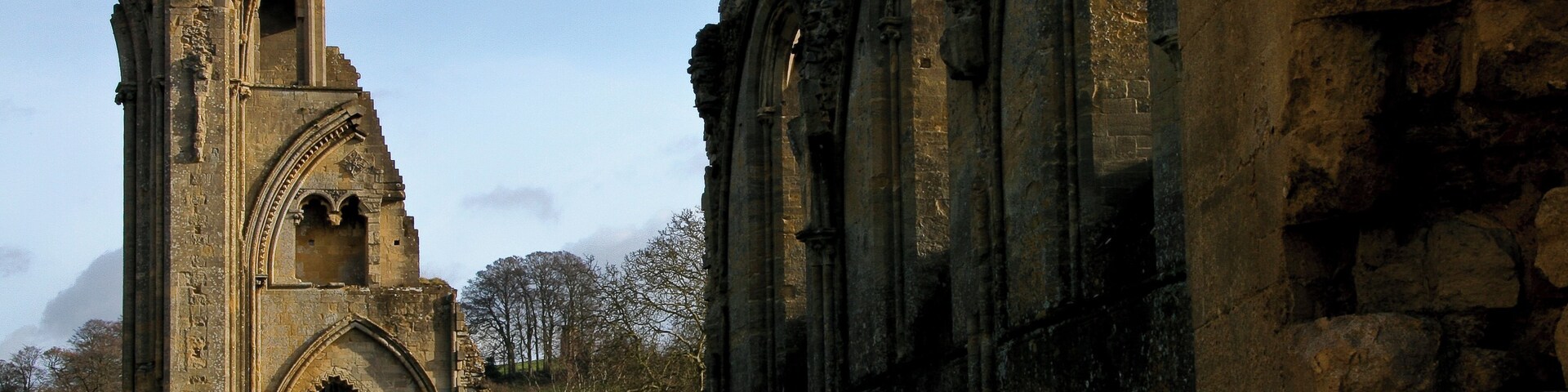 Una antigua iglesia de piedra con ventanas de arco y una alta torre campanario.