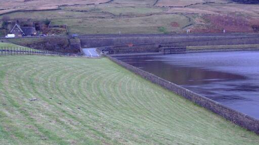 Longdendale in Derbyshire is the valley of the River Etherow. The Longdendale Chain is a series of reservoirs built to provide drinking water forManchester. The Woodhead reservoir is the highest in the chain, and the last to be finished. Taken from the 1992 embankment (6.7m above the 1877 original level) , here is the overflow weir and the B6105 road with the A628 behind. The hill is Hoy Edge. Weather and light difficult. Camera location 53° 29′ 27.52″ N, 1° 52′ 42.24″ W View this and other nearby images on: OpenStreetMap - Google Earth 53.490978; -1.878400