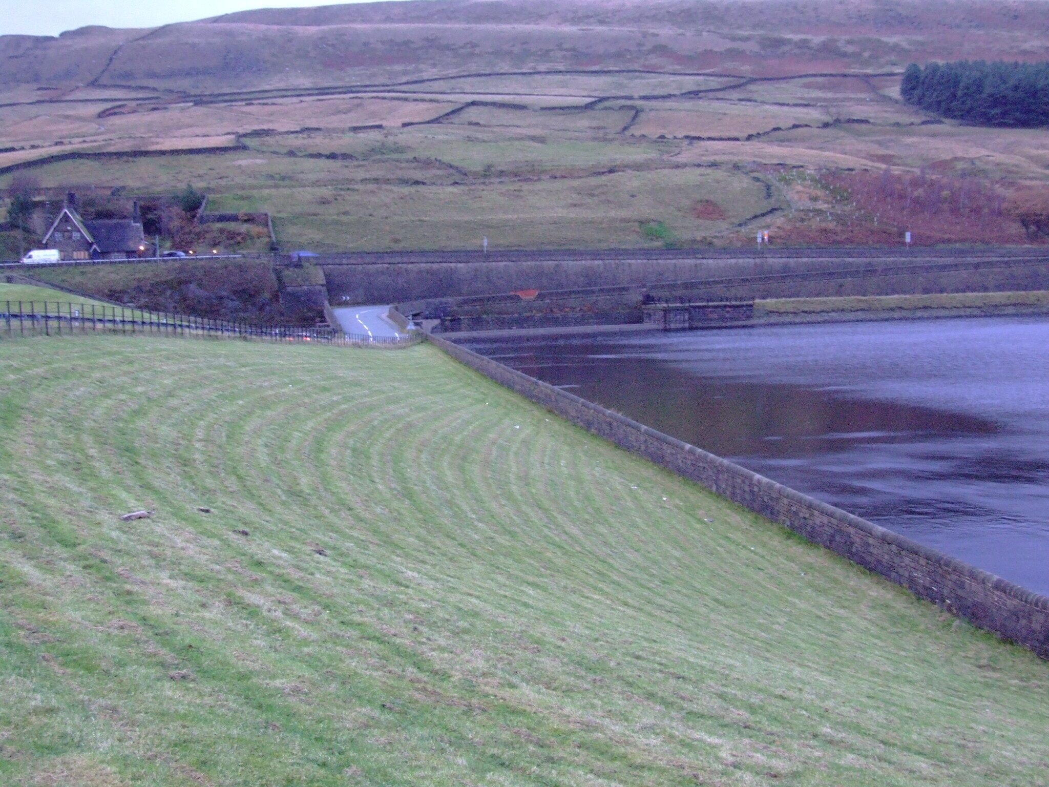 A rural landscape with a river, a bridge, and a house.