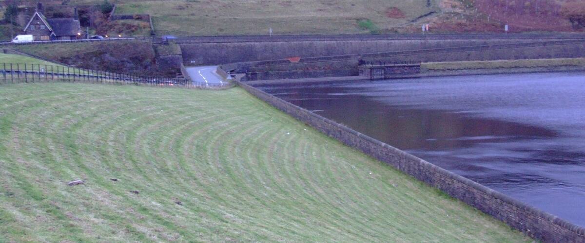 A rural landscape with a river, a bridge, and a house.