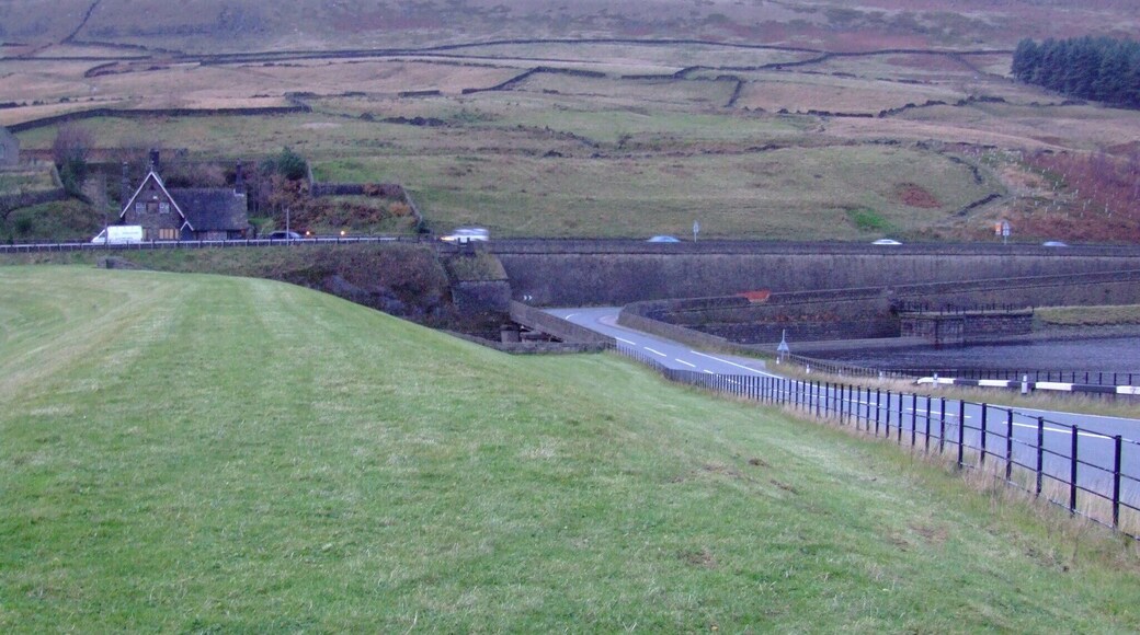 Longdendale in Derbyshire is the valley of the River Etherow. The Longdendale Chain is a series of reservoirs built to provide drinking water forManchester. The Woodhead reservoir is the highest in the chain, and the last to be finished. Taken from the 1992 embankment (6.7m above the 1877 original level) , here is the overflow weir and the B6105 road with the A628 behind. The hill is Hoy Edge. Weather and light difficult. Camera location 53° 29′ 27.48″ N, 1° 52′ 43.63″ W View this and other nearby images on: OpenStreetMap - Google Earth 53.490967; -1.878786