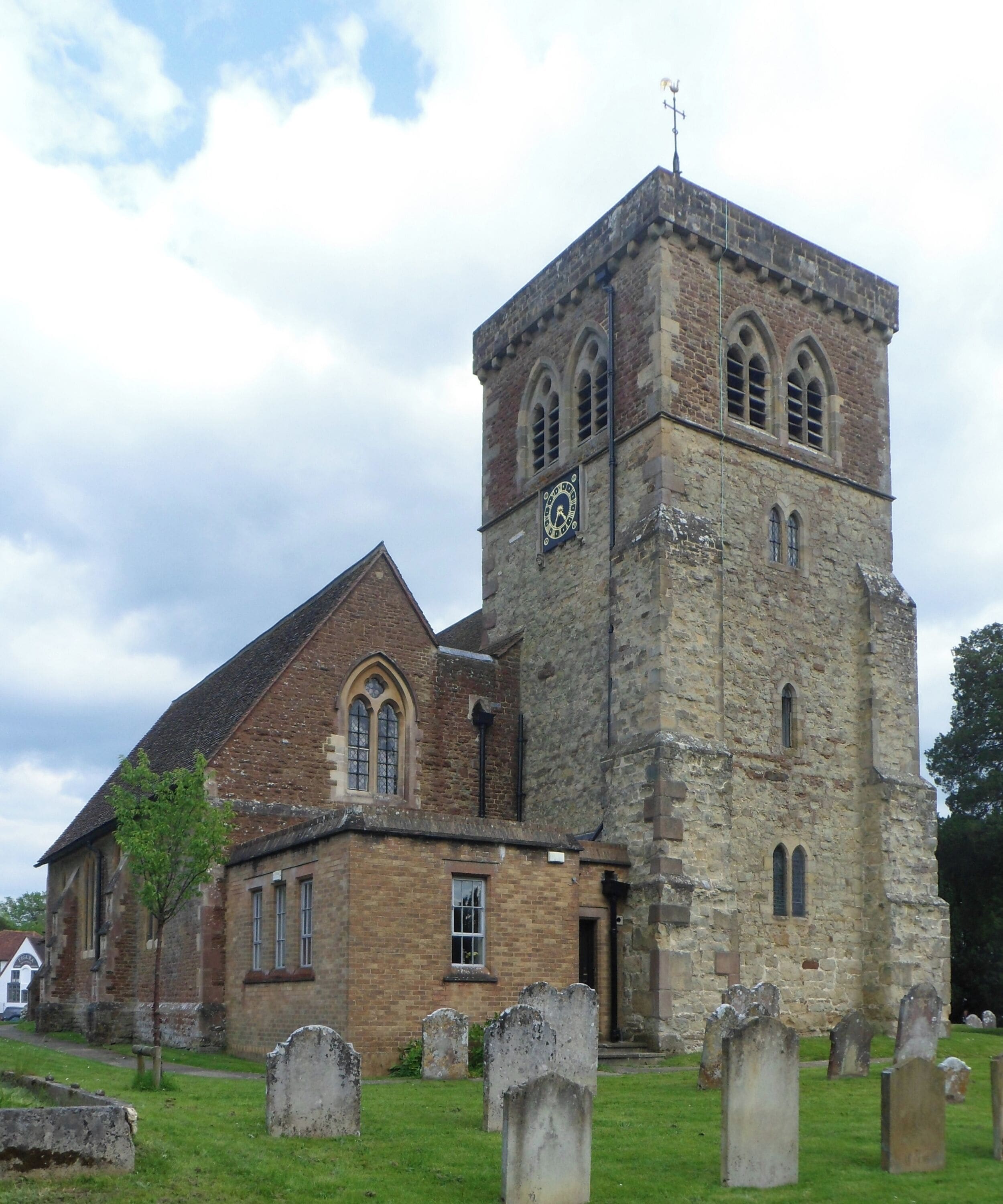 A historic church with a clock tower and a graveyard in front.