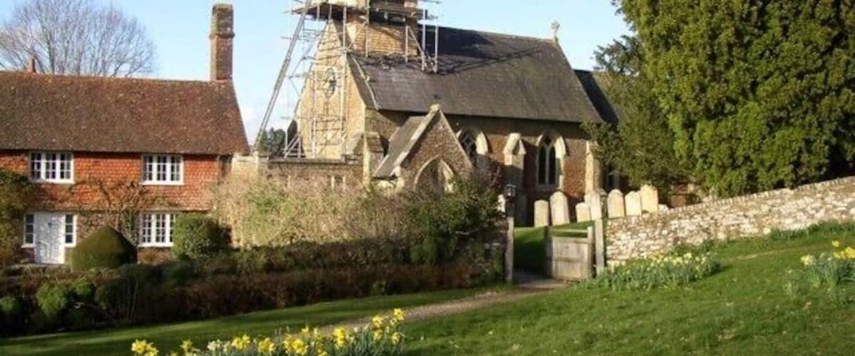 Una iglesia con andamios, una casa de ladrillo rojo y un jardín con narcisos.