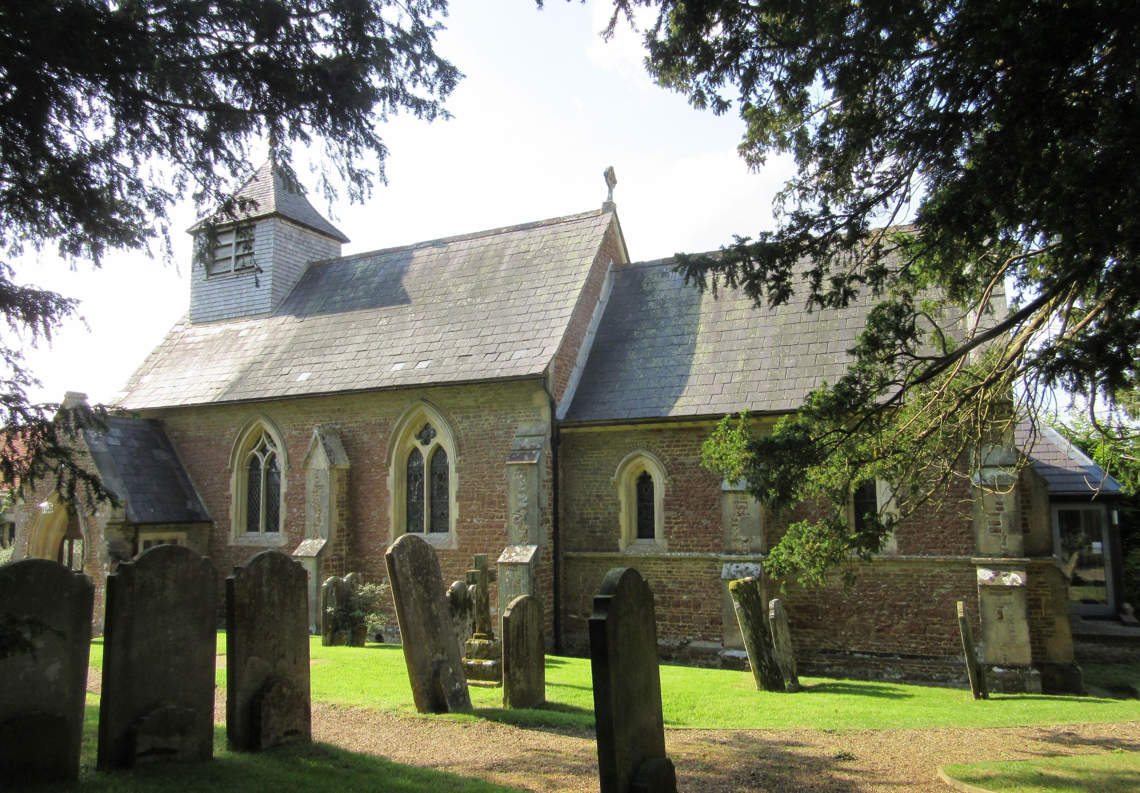 A church with a steeple and a graveyard in front.