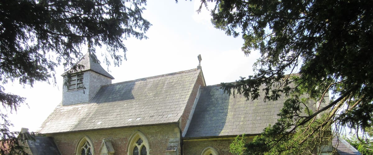 A church with a steeple and a graveyard in front.