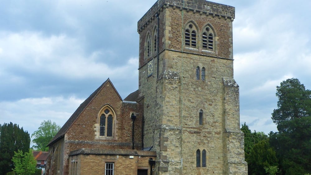 Eine Kirche mit einem markanten Turm und einem Friedhof davor.