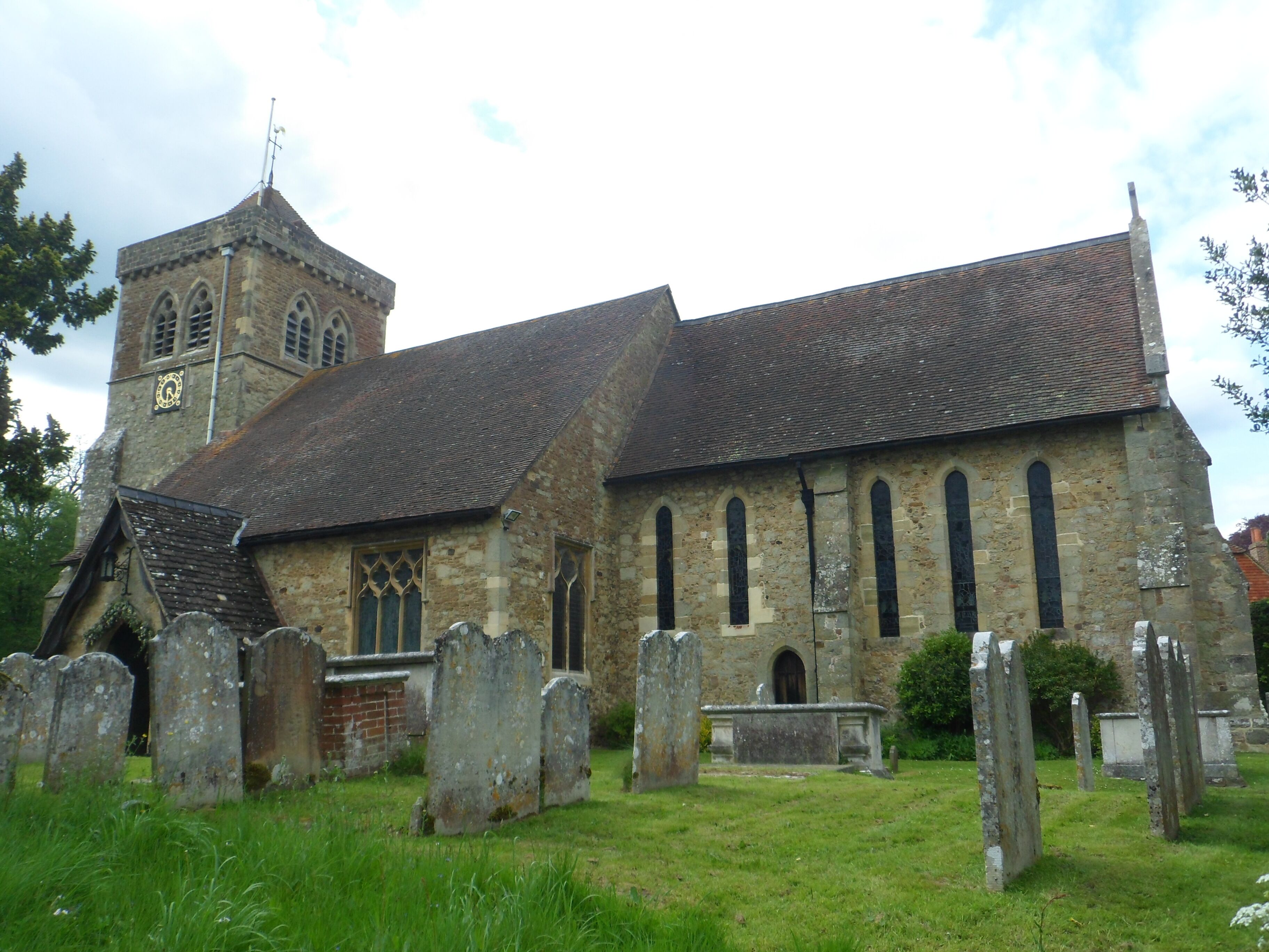 A historic church with a tall bell tower and a graveyard in front.