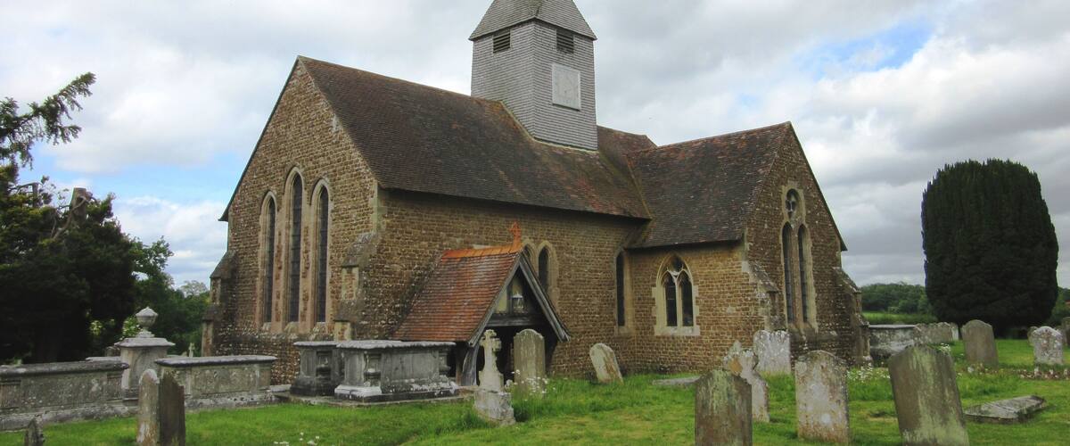 A church with a tall steeple and a graveyard in front.