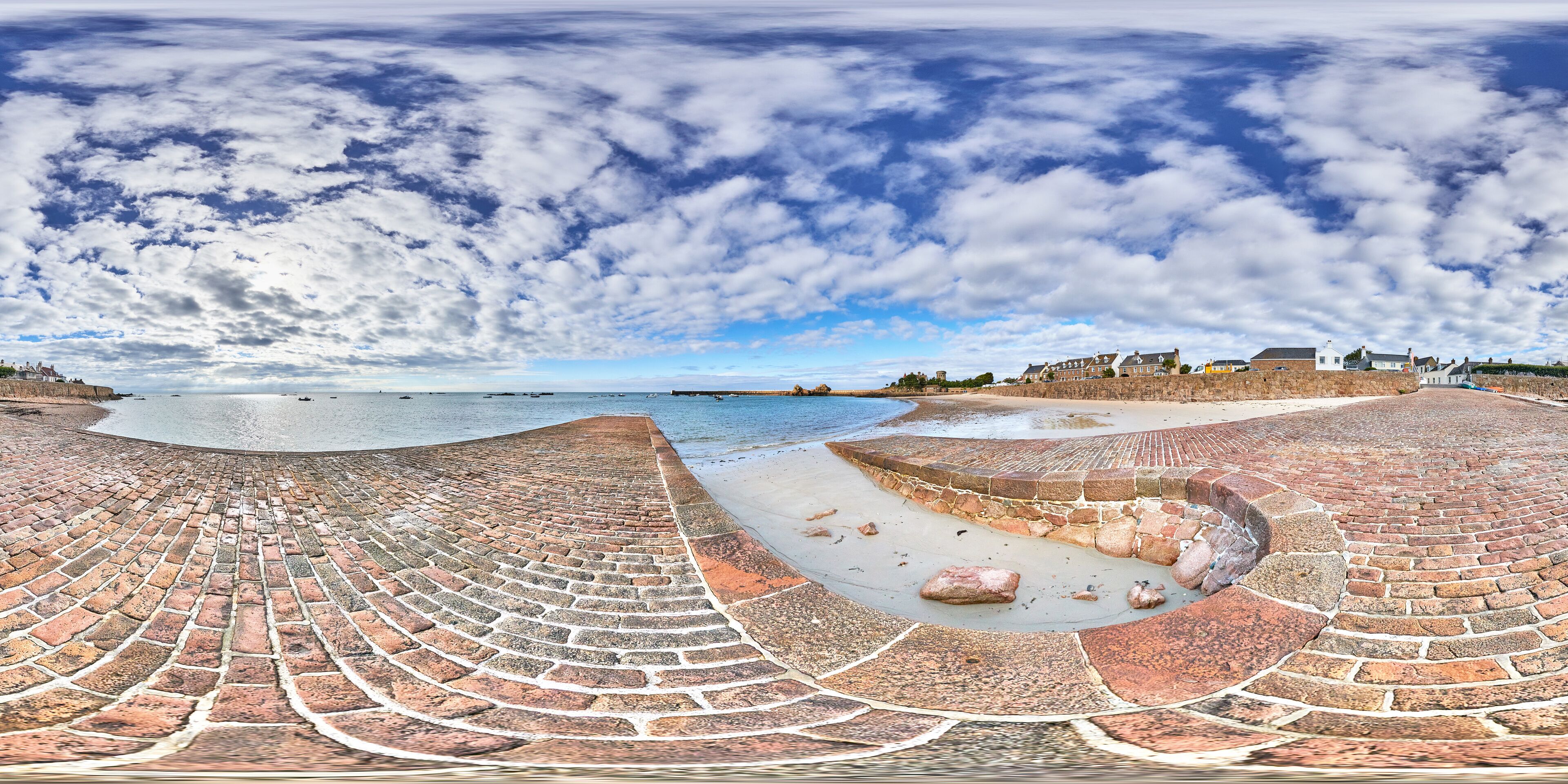 A seaside amphitheater with a curved brick stage and a sandy beach.