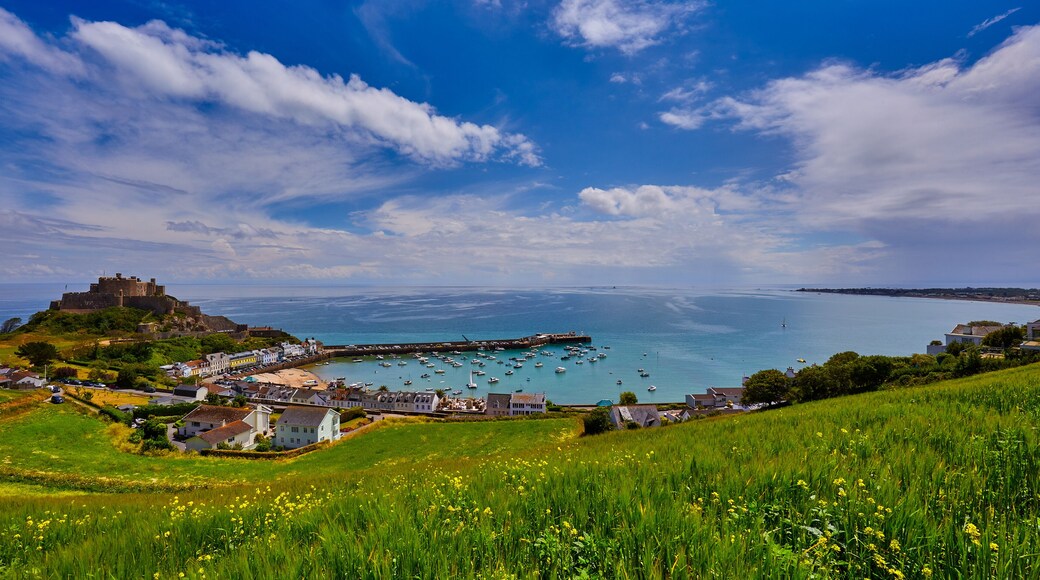 Image of Gorey Castle with Harbour, Grouville Bay calm sea and blue sky and clouds. Jersey, Channel Islands.