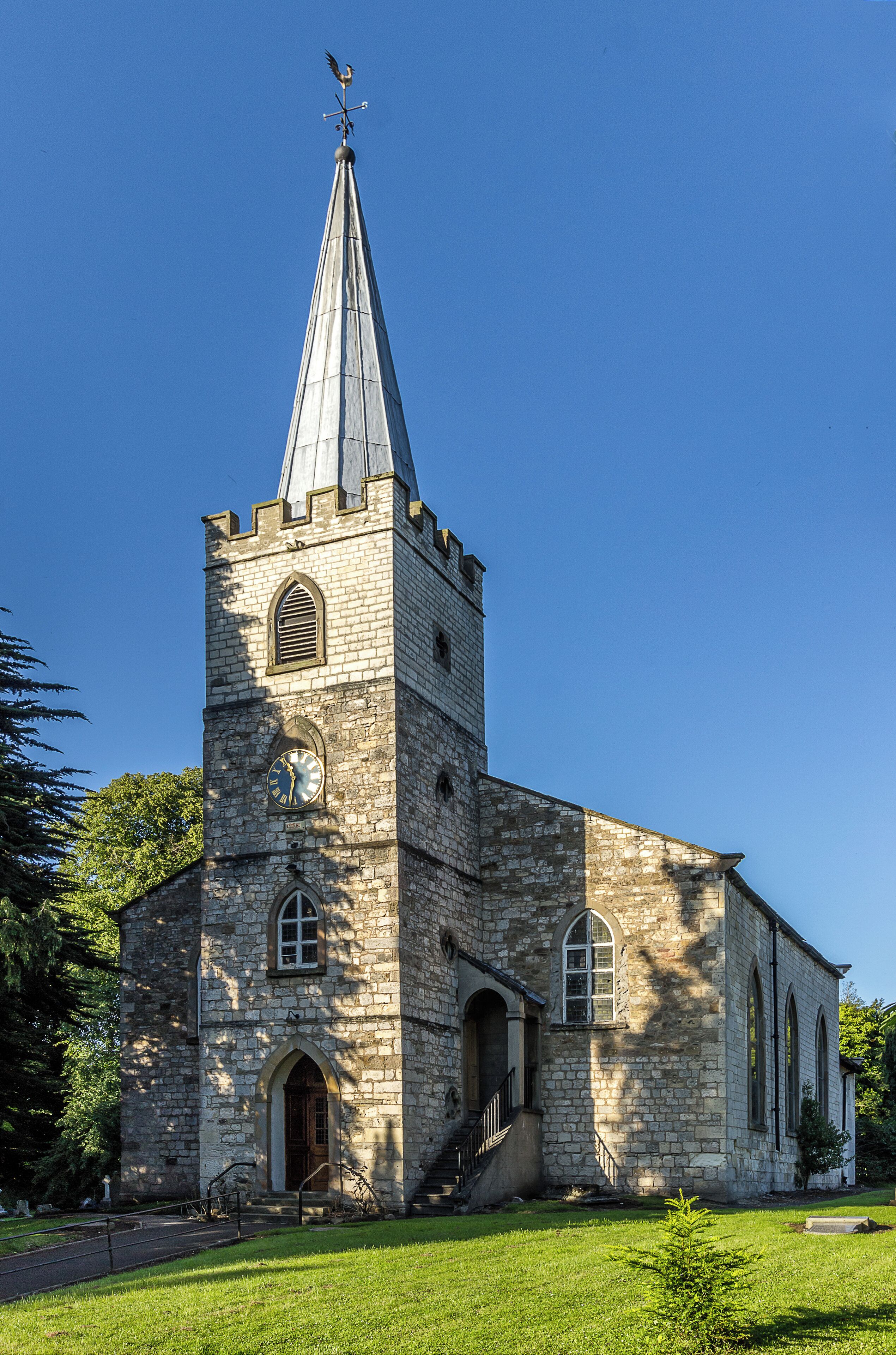 A stone church with a clock tower and a weather vane.