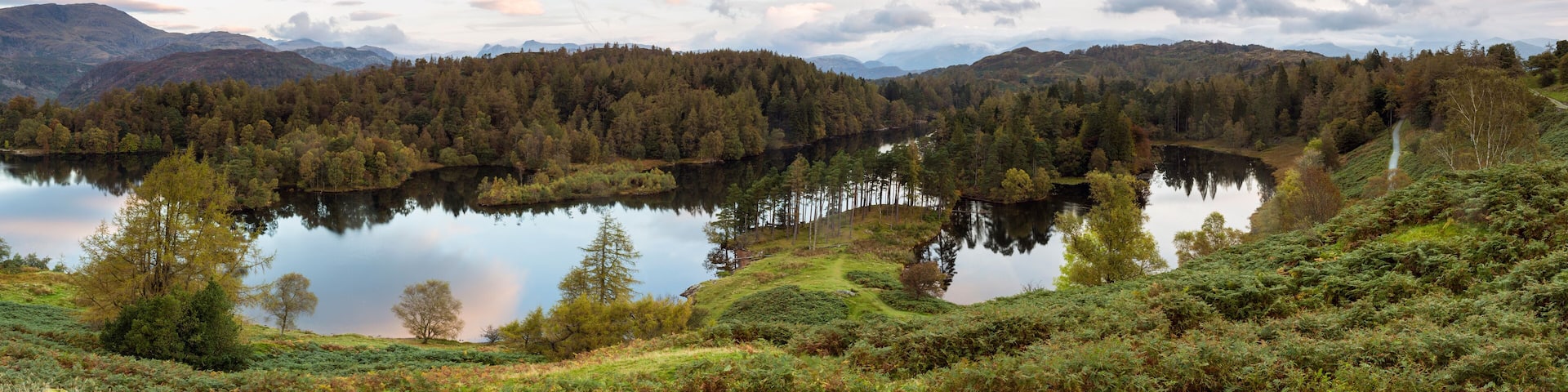 A serene lake surrounded by dense forests and rolling hills.