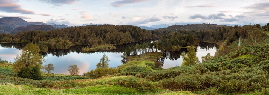 A serene lake surrounded by dense forests and rolling hills.