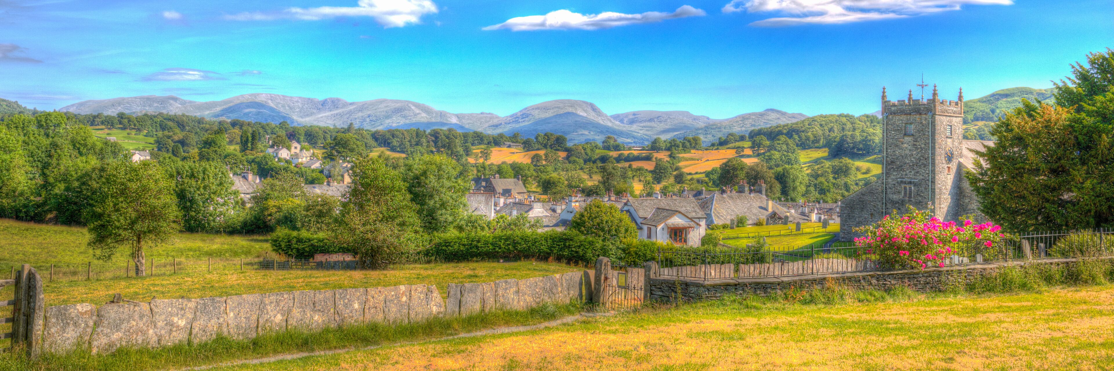 A rural landscape with a stone tower, rolling hills, and scattered houses.
