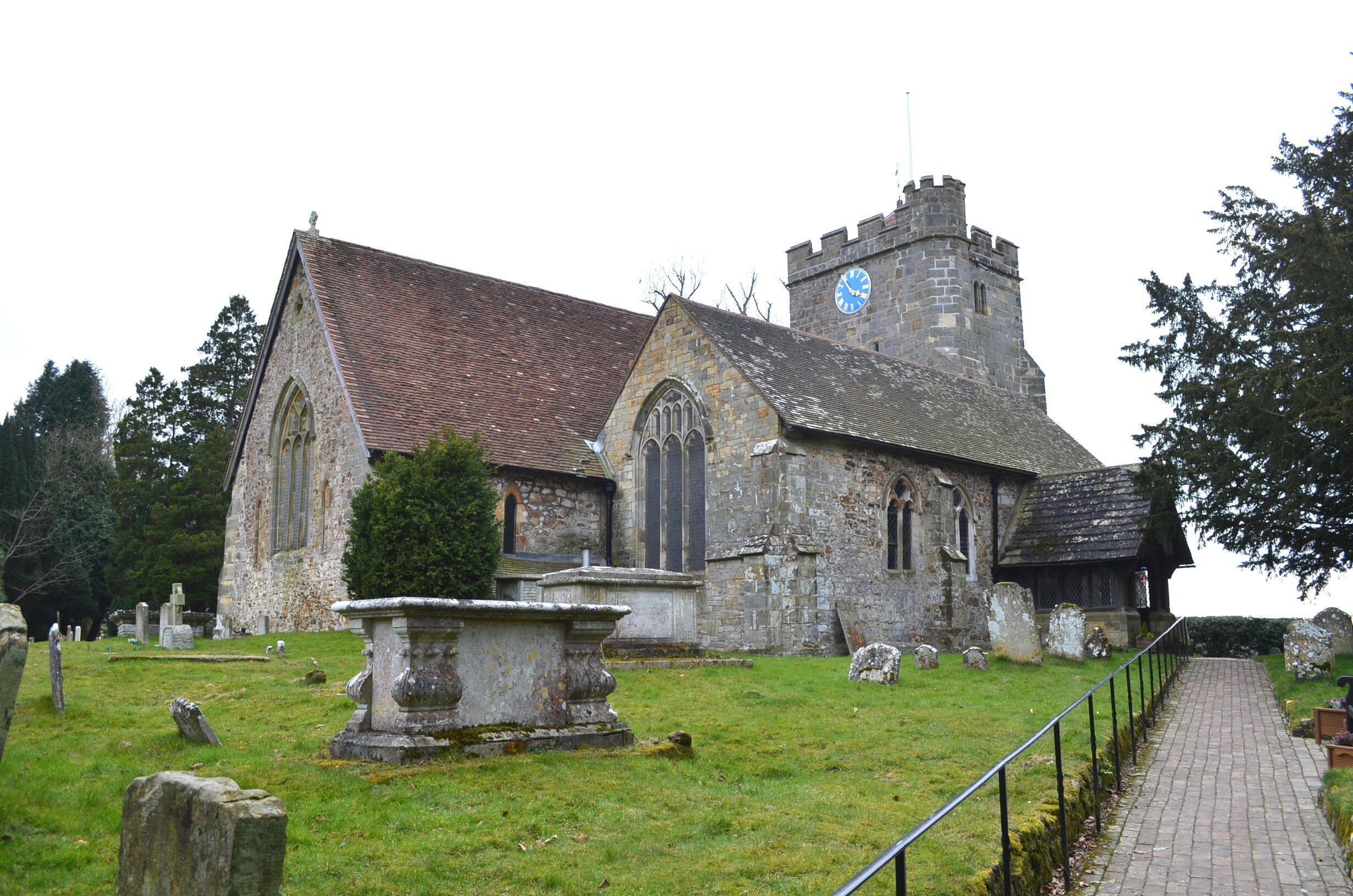 A historic church with a clock tower and a graveyard.