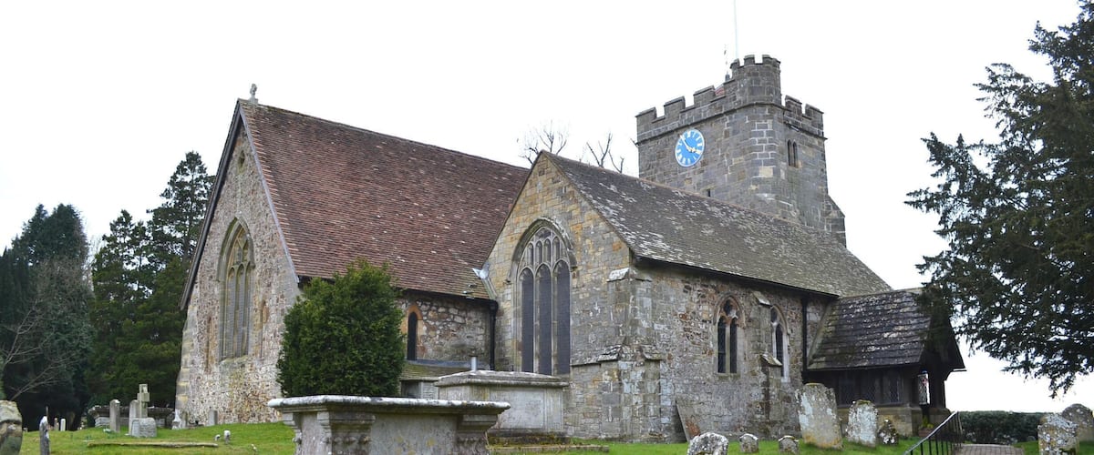 A historic church with a clock tower and a graveyard.