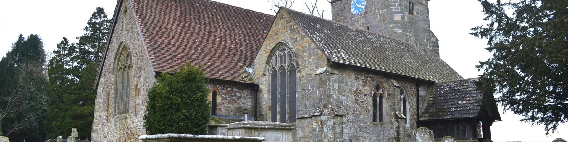 A historic church with a clock tower and a graveyard.
