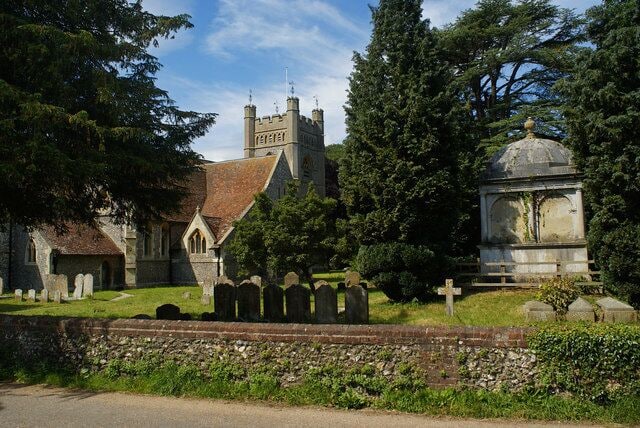 A church with a stone tower, a cemetery with headstones, and a stone monument.