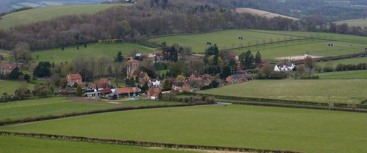 A rural village with rolling hills, fields, and scattered houses.