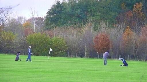 Completing a round Two golfers come towards the end of their round in the fading evening light. The course does slope uphill from right to left at this point.