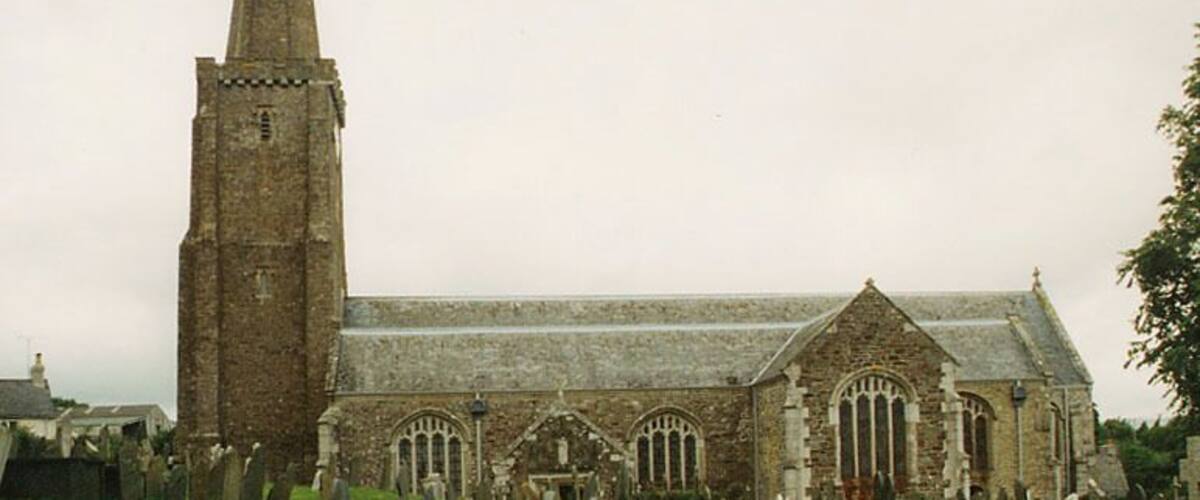 A church with a tall spire and arched windows, surrounded by a cemetery.