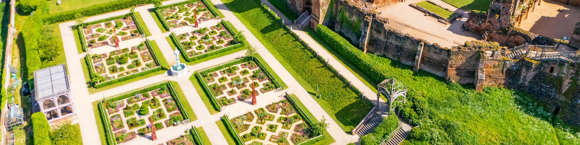 An aerial view of a historic castle with ruins and manicured gardens.
