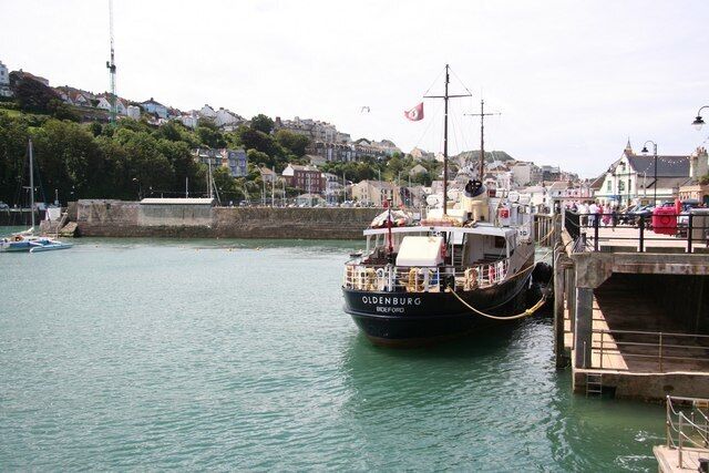 A boat named 'Oldenburg' docked at a pier with a town in the background.