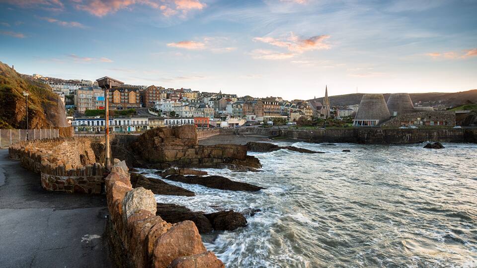 A coastal town with rocky cliffs, a harbor, and historic buildings.