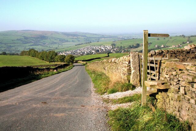 A rural road with a stone wall and a directional signpost.