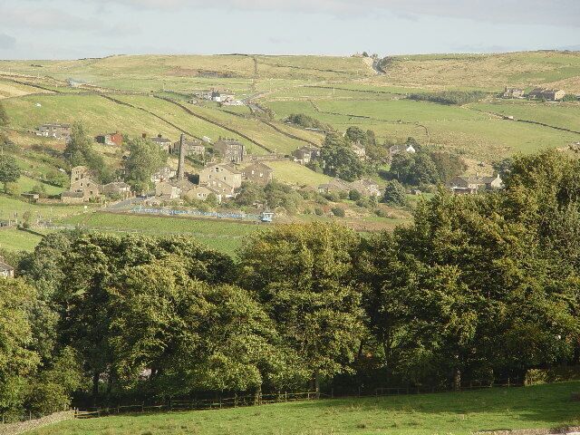 A rural landscape with rolling hills, scattered houses, and a dense tree line in the foreground.