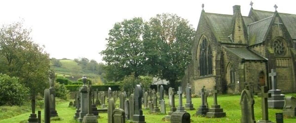 A cemetery with numerous gravestones and a church in the background.