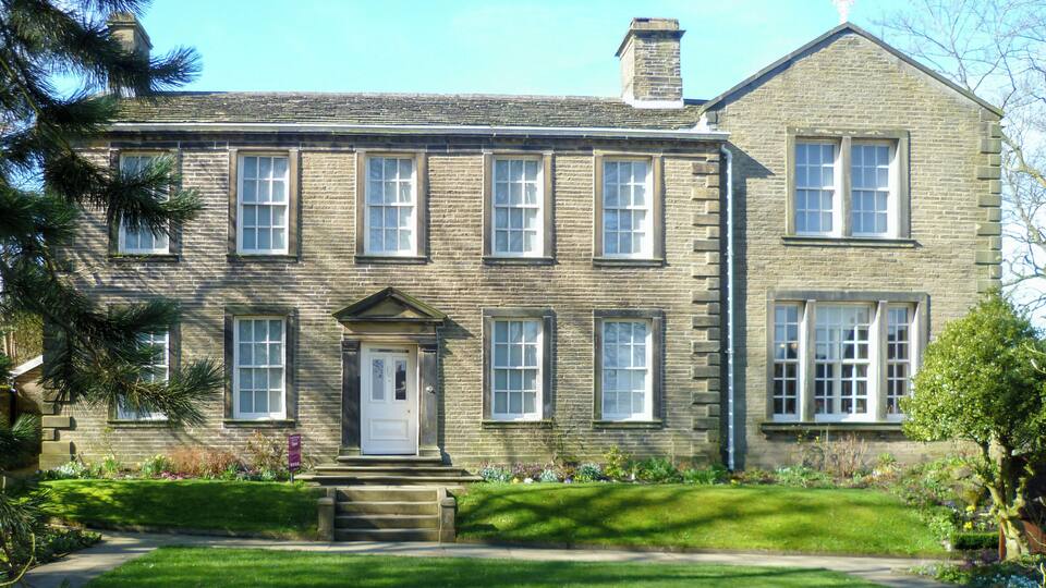 A large stone building with a symmetrical facade, multiple windows, and a central entrance with steps.