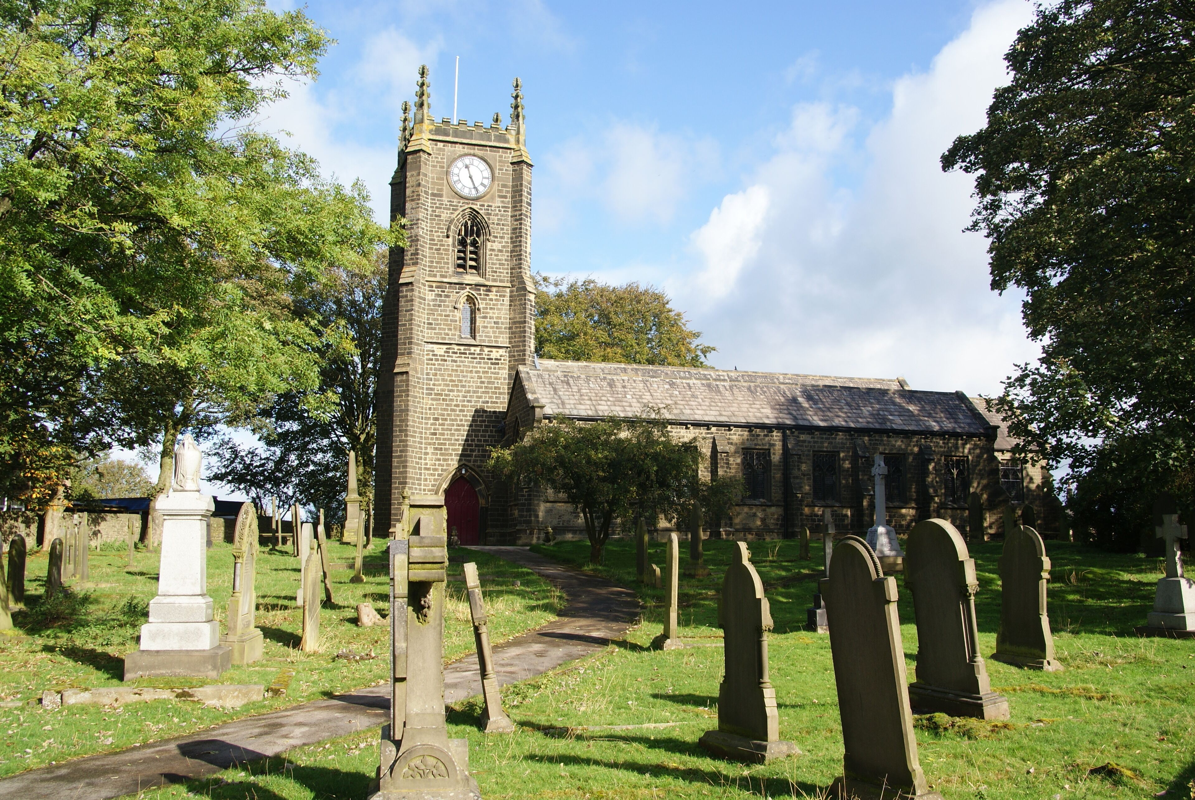 A church with a clock tower and a cemetery with headstones.