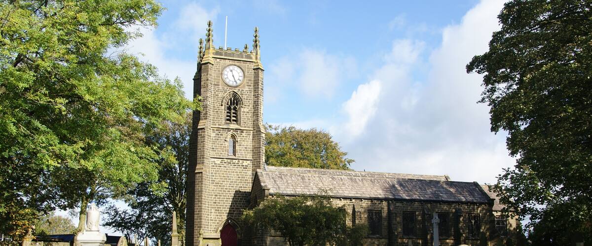 A church with a clock tower and a cemetery with headstones.