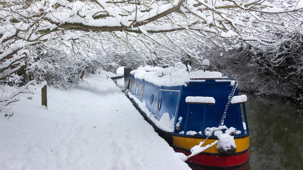Un bateau recouvert de neige était amarré au bord d’une rivière enneigée.