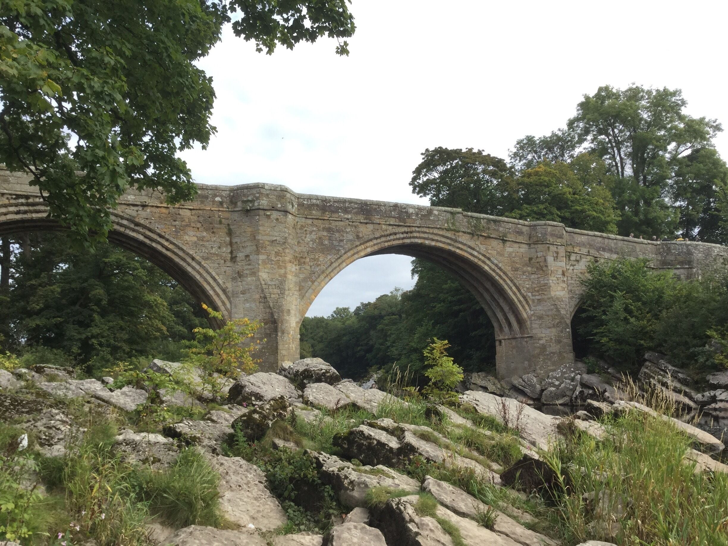 A stone bridge with three arches over a rocky landscape.