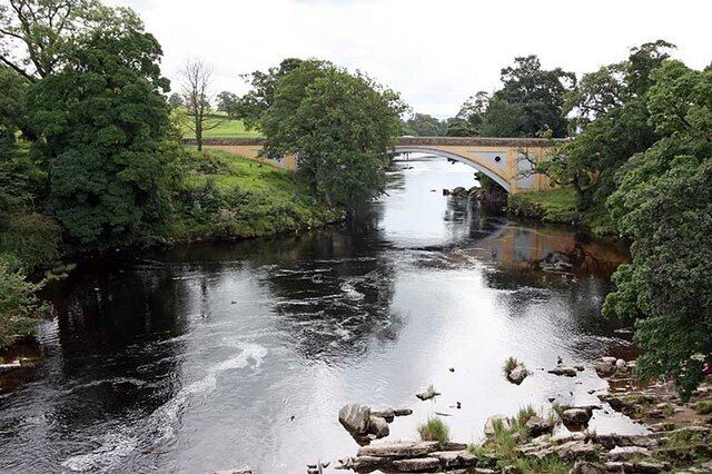 A river with a bridge, surrounded by greenery.