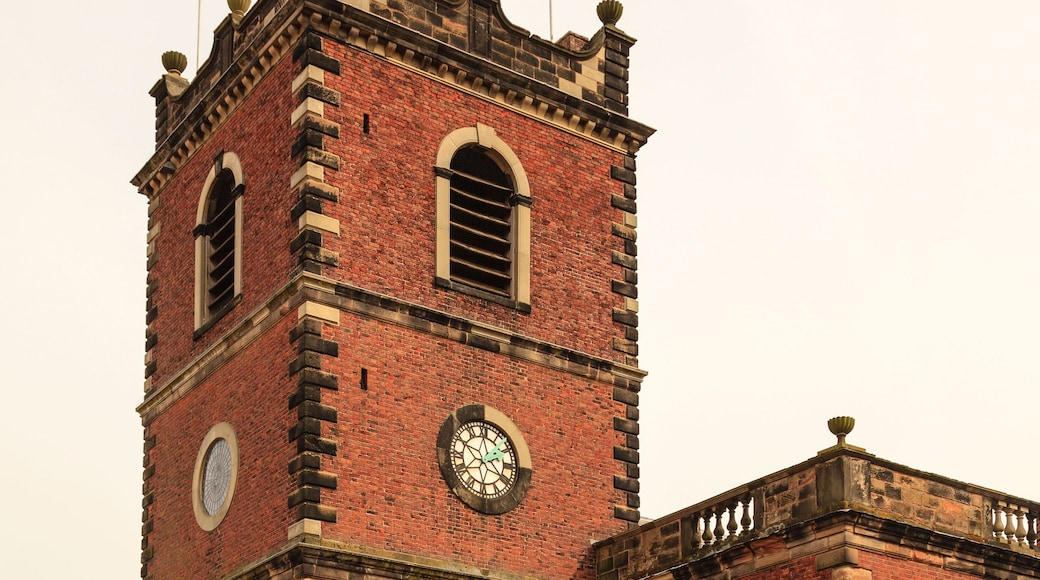 Eine rote Backsteinkirche mit einem Kirchturm, Rundbogenfenstern und einem Friedhof mit Grabsteinen.