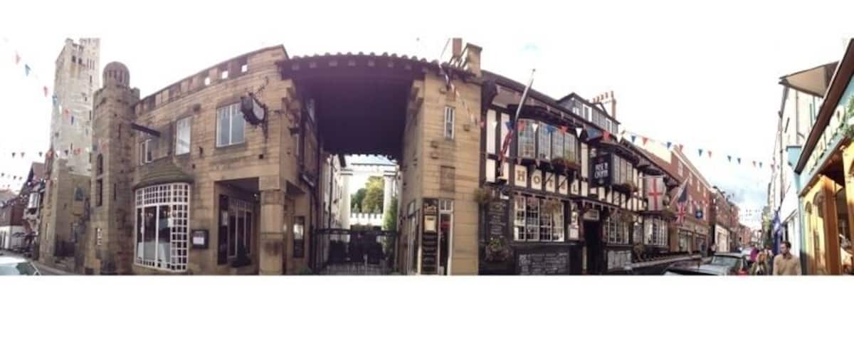 A historic building with a large archway, traditional architecture, and a river in the background.